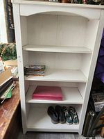 Tall white bookcase with four shelves visible