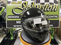 Front angle of black CKX Tranz 1.5 EDL helmet on stand showing clear heated visor and size label