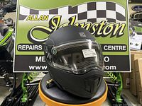 Front-left view of matte black CKX Tranz 1.5 modular snowmobile helmet showing heated shield and sun visor sticker