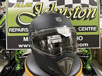 Front view of CKX Tranz RSV matte black modular helmet on stool in store display