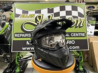 Black CKX Titan AMX helmet with Apex goggles displayed on stand