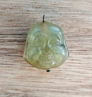 Front view of jade Buddha head pendant showing facial carving and bail