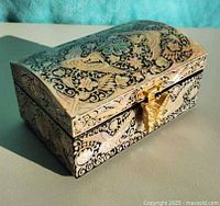 Three-quarter view of closed jewelry box showing inlaid design and clasp