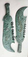 Full view of both green stone dragon swords showing overall shape and carving