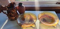 Group shot showing copper lustre jug, terracotta vase and two amber koi plates