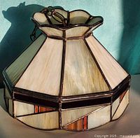 Three-quarter view of pendant light showing scalloped top and geometric glass panels
