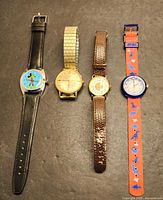 Full view of four wristwatches side by side on black surface