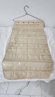 Full front view of beige/cream hanging jewelry organizer with clear pockets