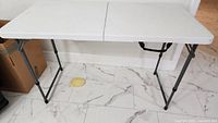 Full view of folded-out white plastic table on tiled floor