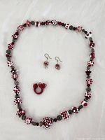 Full view of necklace, earrings and ring laid flat