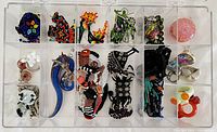 Assorted jewelry pieces organized in clear plastic case showing bracelets, rings, earrings, pendants