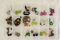 Overall view of 20-compartment plastic tray showing entire assortment of beads, earrings, cufflinks, charms and bracelet