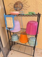 Full lot showing shelf with colored pots, sun decor, saucer, tray