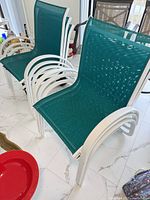 Stacked teal sling chairs showing white frames and mesh
