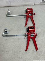 Two identical Tooltech Xpert red cradle caulking guns, full view
