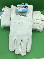 Front view pair of grey leather welding gloves with TWXpert logo and two additional folded pairs beneath