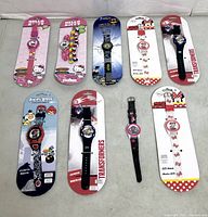 Overview of nine children’s watches on table, eight carded, one loose