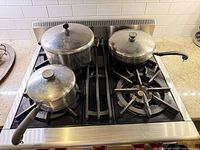 All three aluminum pots and pans with lids shown on stovetop