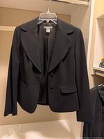 Front view of black Ann Taylor blazer on hanger showing lapels, buttons, pockets