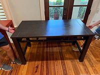 Full view of dark brown rectangular desk held at both ends