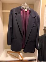 Front view of dark blue blazer on hanger showing lapels, pockets, lining