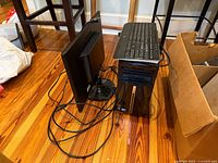 Desktop tower, monitor rear, keyboard, cables on floor