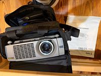 Projector in open carrying case with manual beside