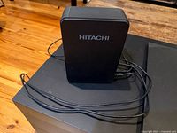 Front and side view of black Hitachi external hard-drive enclosure with cables