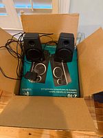 Pair of black Logitech Z-10 speakers with cables, power adapter and packaging inside cardboard box