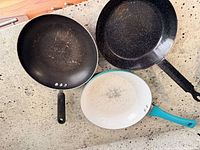 Top view of three frying pans showing interiors and handles