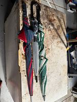 Three closed umbrellas laid side by side on workbench