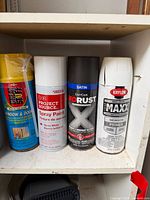 Front view of four aerosol cans on shelf