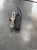 Belkin black surge protector and off-white power strip on floor