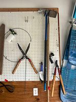 Full view of five garden tools on pegboard