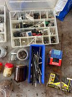 Overview of clear organizer box with compartments, blue organizer, jars and boxed fasteners