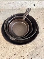 Nested stack of four cast iron skillets showing varying sizes