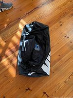 Top view of black Nike duffel showing Duke Tennis logo pocket and swoosh on side panel
