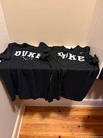 Two black Nike Duke long-sleeve tees displayed side by side