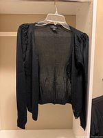 Front view of black sheer cardigan on hanger