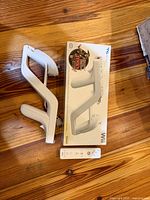 Wii Zapper halves, retail box, and one Wii Remote on wood floor