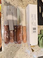 Five factory-wrapped steak knives beside original Oneida box