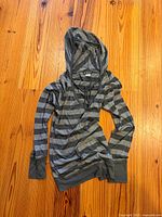 Full view of gray striped hoodie laid flat showing front, sleeves, and hood