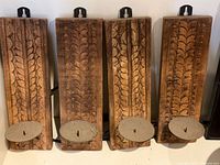 Front view of all four carved wooden sconces showing carving detail, metal plates, and spikes