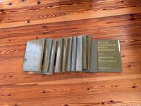 Entire row of 11 green cloth volumes on wood floor, front cover of one volume visible