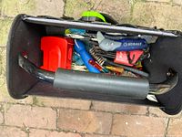 Top view of open bag showing black exterior, yellow interior, padded handle and assorted tools