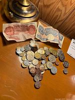 Group shot of two Bank of England notes and pile of assorted coins on wooden surface