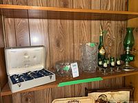 Shelf view showing all items: Moser case, cut-crystal bowl and vase, painted decanter set, oil lamp