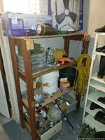 Wood shelf holding boxed ceiling fan, square floor fan, organizer, bucket, extension cord and various hardware