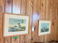 Both framed prints on wood-panel wall