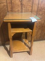Front view of wooden three-tier side table with glass top